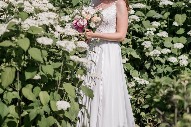 Sposa in un abito da sposa in fiori nel parco