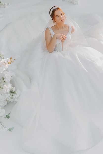 sposa in un tradizionale abito bianco con un bouquet da sposa accanto all'arco nuziale