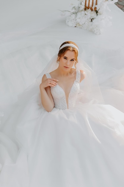 sposa in un tradizionale abito bianco con un bouquet da sposa accanto all'arco nuziale