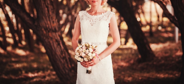 Sposa in un vestito bianco che tiene un mazzo di fiori