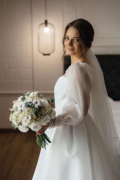 Sposa in un vestito da sposa bianco che tiene un mazzo di fiori