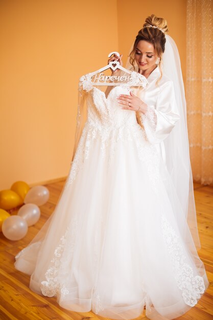 Sposa in vestito bianco che posa mentre preparando per la cerimonia di nozze