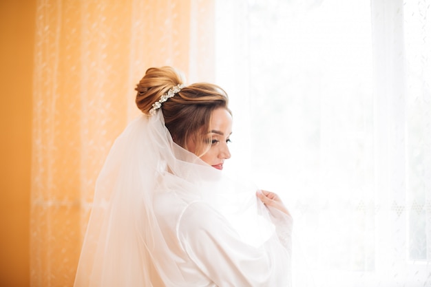 Sposa in vestito bianco che posa mentre preparando per la cerimonia di nozze