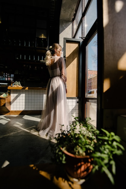 Sposa in vestito da sposa bianco che posa all'interno