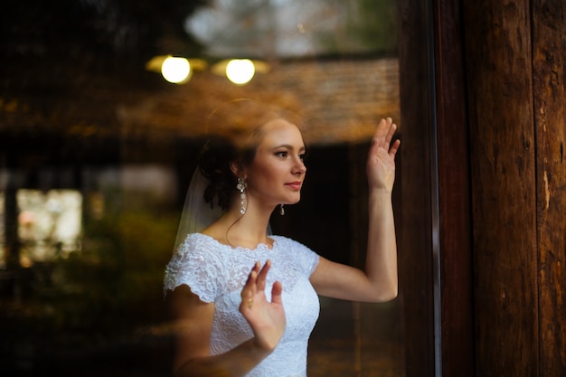 Sposa indossata in abito sopra la finestra. giorno soleggiato. luce del sole