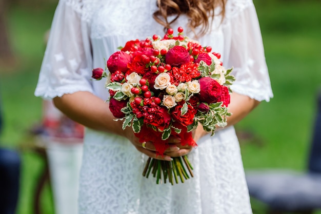 Sposa nel mazzo bianco della tenuta del vestito in mani