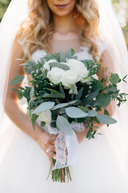 Sposa nel mazzo bianco della tenuta del vestito