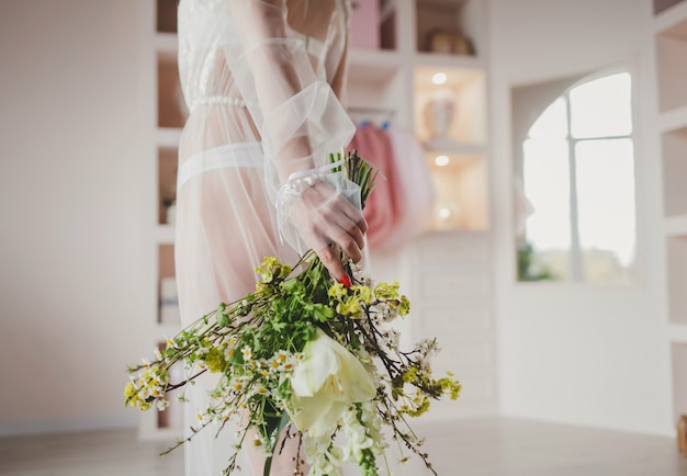 Sposa nel mazzo della tenuta del vestito da sposa.