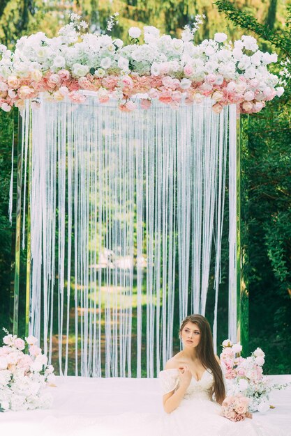 Sposa vicino ad arco di nozze con fiori