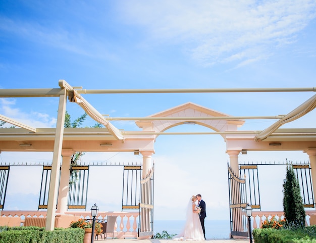 Sposi di lusso si trova sotto il portico con vista sul mare alle spalle