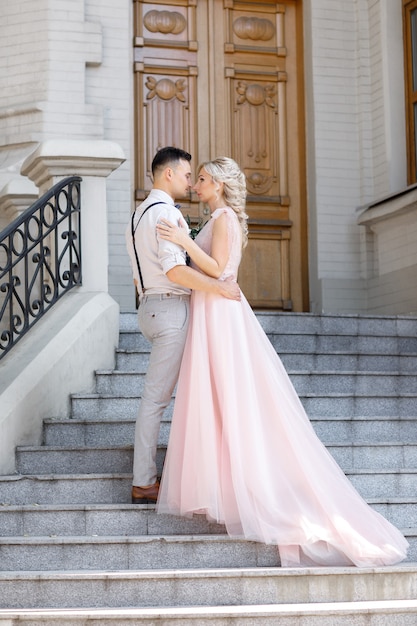 Sposi in città nella soleggiata giornata estiva. la sposa e lo sposo che abbracciano sulle scale