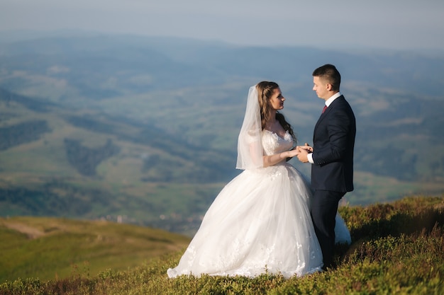 Sposi in montagna. Sposa e sposo in piedi sulla collina