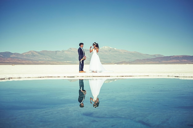 Sposi in posa nel paesaggio bianco con vestito e vestito