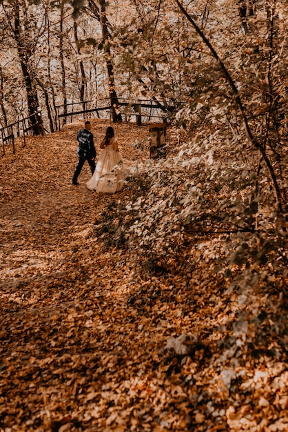 Sposi innamorati uomo e donna che cammina nella foresta di autunno