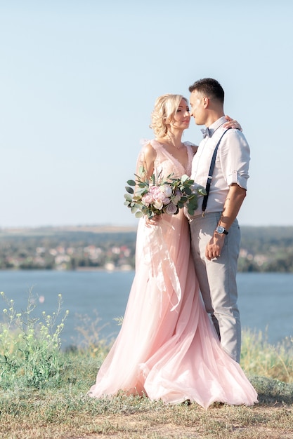 Sposi sulla natura nel giorno d'estate. la sposa e lo sposo che abbracciano al matrimonio.