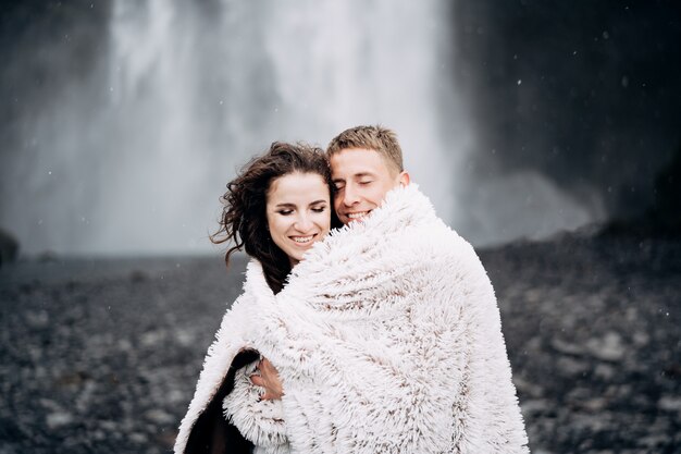 Sposi vicino alla cascata skogafoss la sposa e lo sposo coperti con una coperta di lana dove