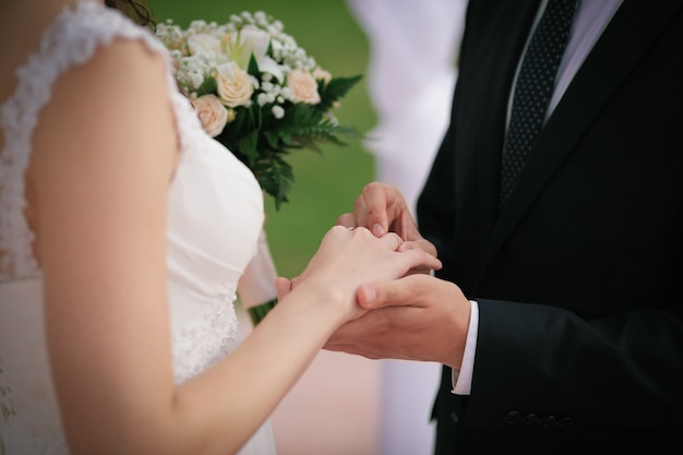 Sposo che mette una fede nuziale sul dito della sposa