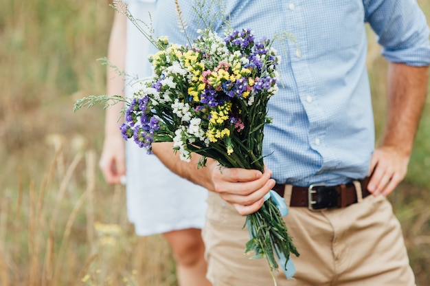 Sposo che tiene bellissimo bouquet di fiori selvatici