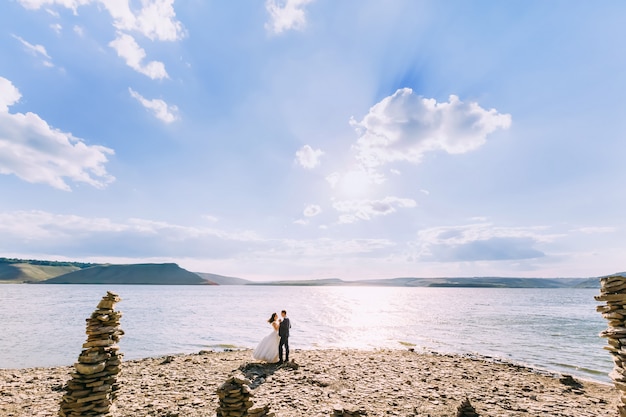 Sposo e sposa che godono della giornata calda su un lago il giorno ventoso