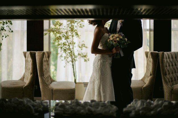 sposo e sposa in un ristorante moderno ed elegante. la sposa tiene in mano un bouquet da sposa.