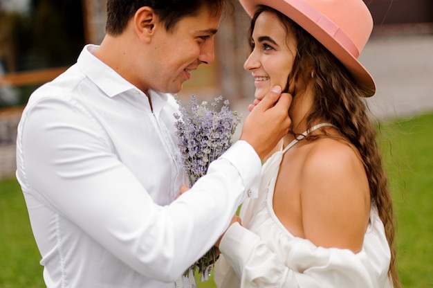 Sposo in camicia bianca e bella sposa in abito bianco amorevolmente guardando l'altro