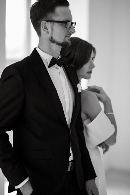 Sposo in cravatta nera e sposa in uno studio luminoso