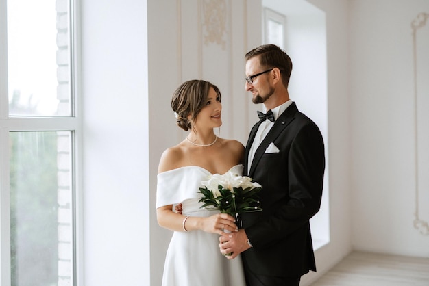 Sposo in cravatta nera e sposa in uno studio luminoso