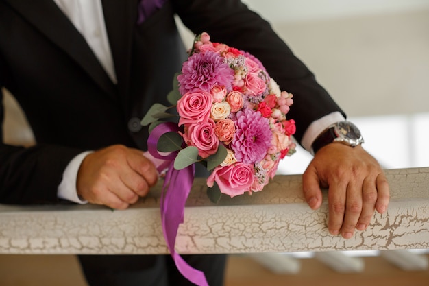 Sposo in vestito tenere bouquet da sposa per la sposa. uomo che si prepara per un appuntamento romantico con i fiori si chiuda