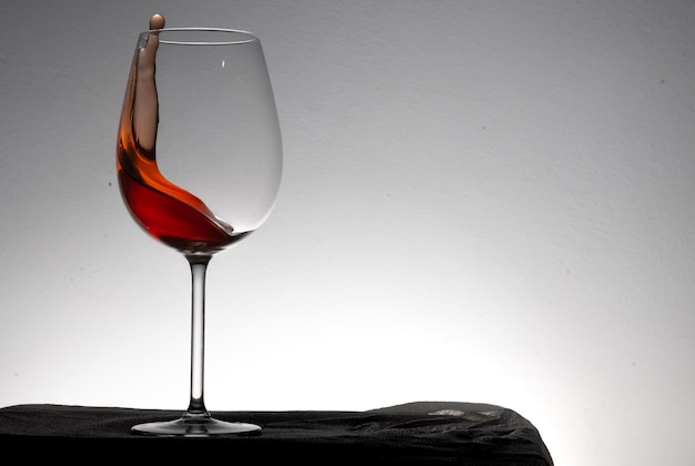 Spostamento di un bicchiere di vino rosso su uno sfondo bianco