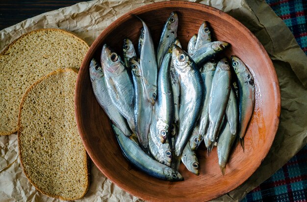 Spratto salato in una ciotola e pane integrale