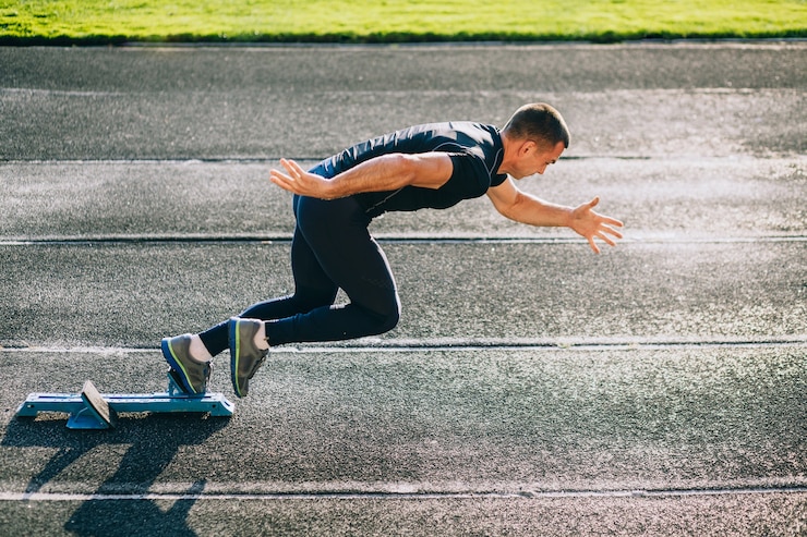 Foto sprinter lasciando blocchi di partenza sulla pista di atletica