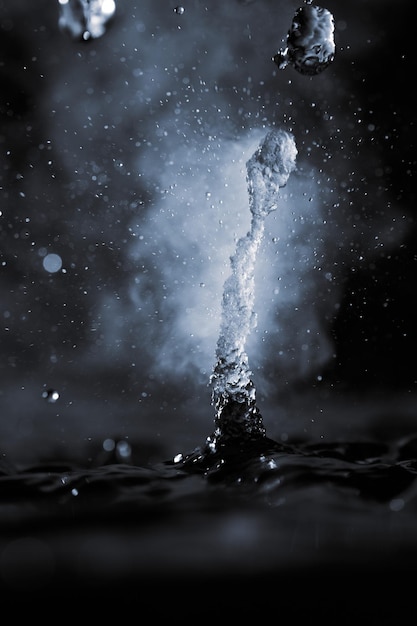 Spruzzata dell'acqua bollente con vapore sul primo piano nero del fondo