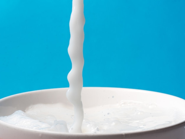 Spruzzata di latte da una tazza su sfondo blu.