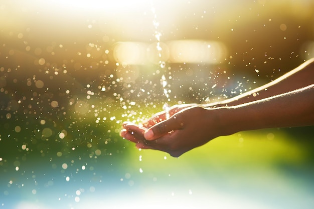 Spruzzi d'acqua Colpo del primo piano delle mani tese sotto un flusso d'acqua