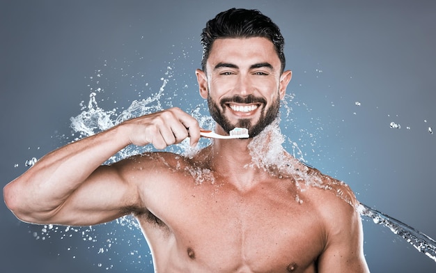 Spruzzi d'acqua lavarsi i denti e ritratto dell'uomo con spazzolino da denti benessere dentale e cura della bocca sana Pulizia orale del modello maschile felice e alito fresco per la felicità del sorriso e cosmetici per la doccia