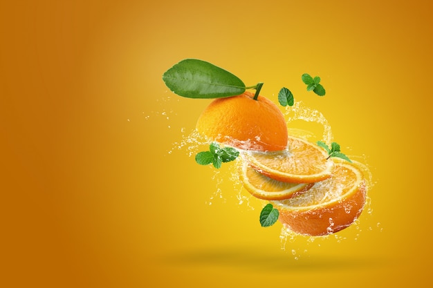 Spruzzi d'acqua su fette di frutta fresca su sfondo arancione