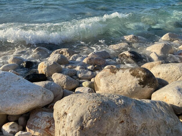 Spruzzi di acqua di mare e schiuma sulla riva di pietra