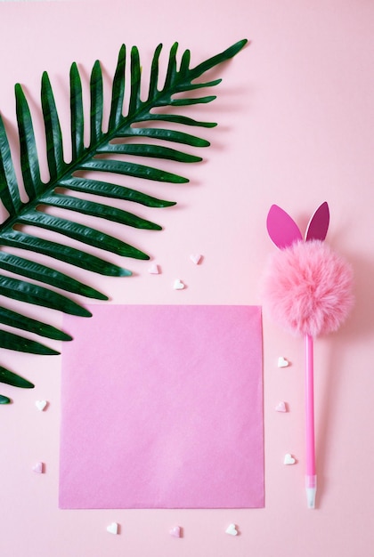 Spruzzi di caramelle a forma di foglio vuoto e ramo di palma su uno sfondo rosa