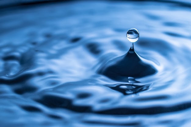 Spruzzi di gocce d'acqua in un bicchiere di colore blu