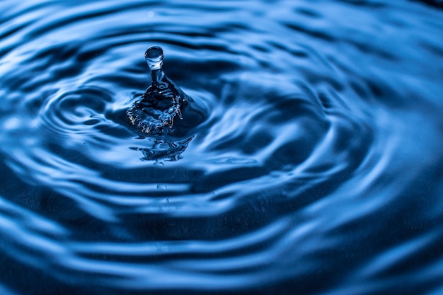 Spruzzi di gocce d'acqua in un bicchiere di colore blu