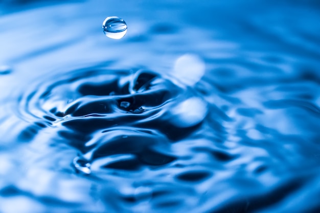 Spruzzi di gocce d'acqua in un bicchiere di colore blu