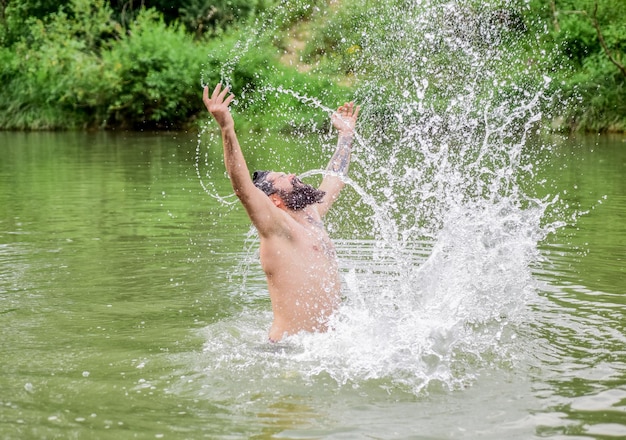 Spruzzi di libertà L'uomo si diverte a nuotare nel fiume o nel lago Immergersi nell'acqua Freschezza della natura selvaggia Vacanze estive Acque profonde e pericolose Relax e riposo Sport di nuoto Abilità di nuoto