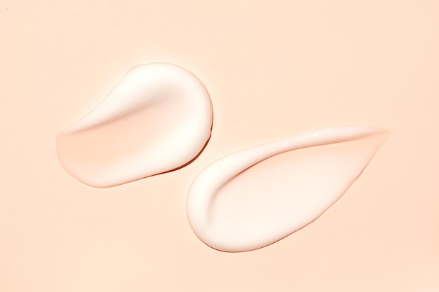 Spruzzo di prodotto cosmetico lozione idratante bianca isolata su beige porzione schiacciata e spruzzata di crema per la cura della pelle test del prodotto