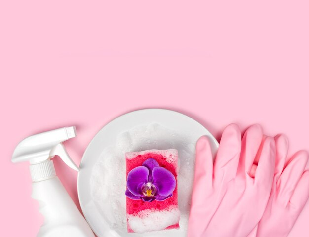 Spugna da cucina detergente guanti di gomma rosa piastra di sapone e fiore di orchidea sullo sfondo rosa