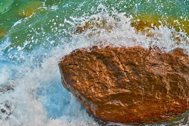 Spuma del mare e una grande pietra in schiuma bianca in primo piano