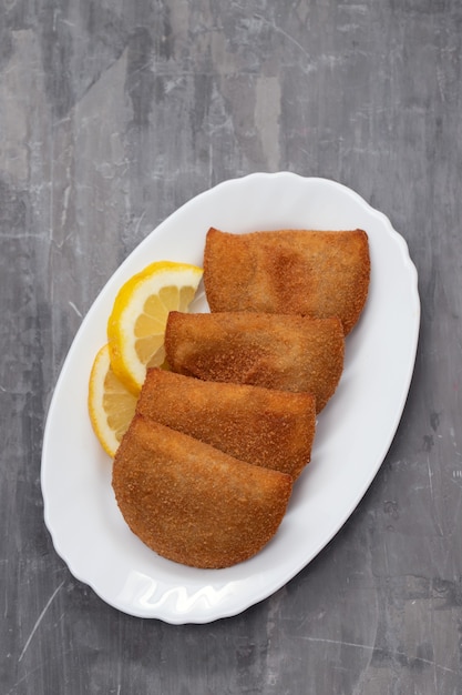 Spuntini di carne portoghesi sul piatto bianco su fondo in ceramica