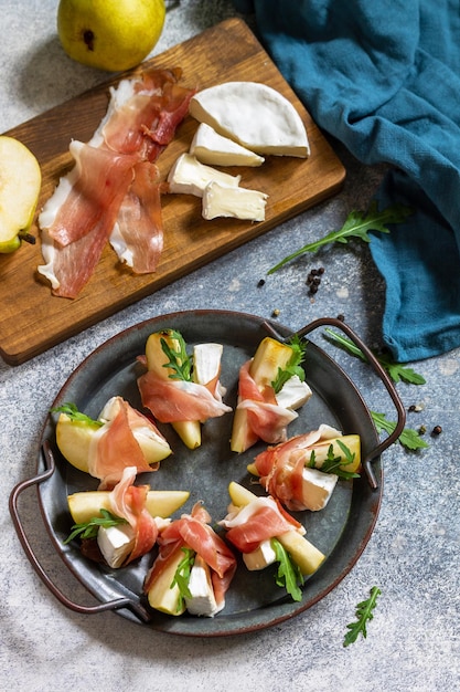 Spuntini estivi Antipasto di pere con rucola jamon e formaggio brie su un tavolo di pietra chiara Vista dall'alto