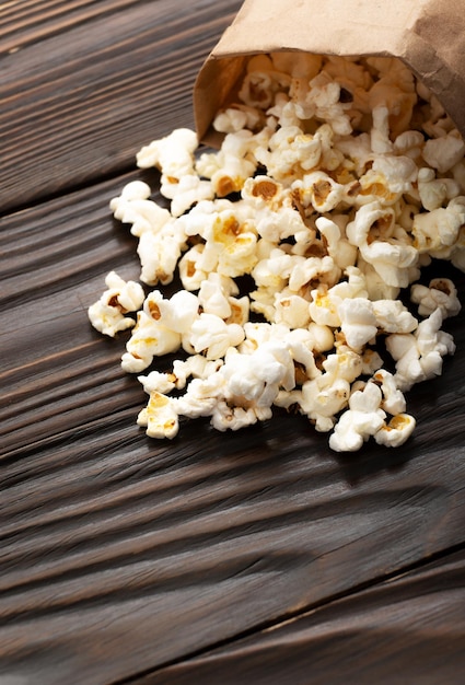 Spuntino di mais schioccato nel sacchetto di carta sul primo piano della tavola di legno