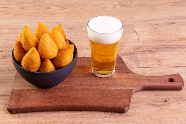 Spuntino fritto tradizionale brasiliano a base di pollo noto come "coxinha" e un bicchiere di birra