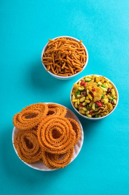 Spuntino indiano: Chakli, Chakali o Murukku e Besan (farina di Gram) Sev e chivada o chiwada su sfondo blu. Diwali Food